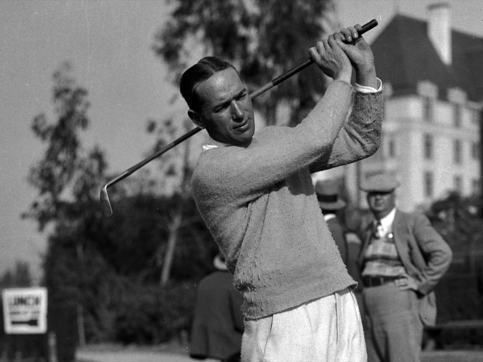 A golfer swinging at the Wilshire Country Club in the late 1920s, with the clubhouse in the background