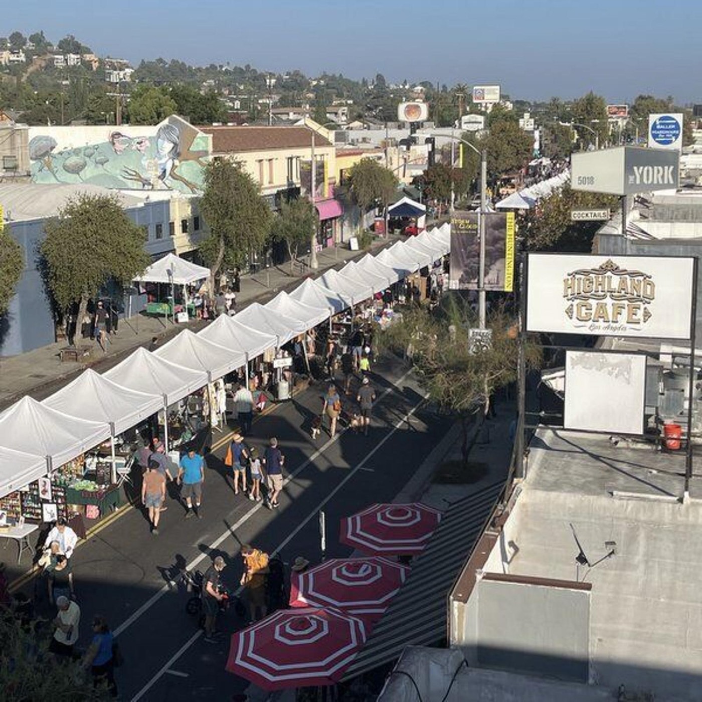 York Boulevard in Highland Park lined with market tents and pedestrians during the El Mercado street festival, Highland Cafe and The York signage visible