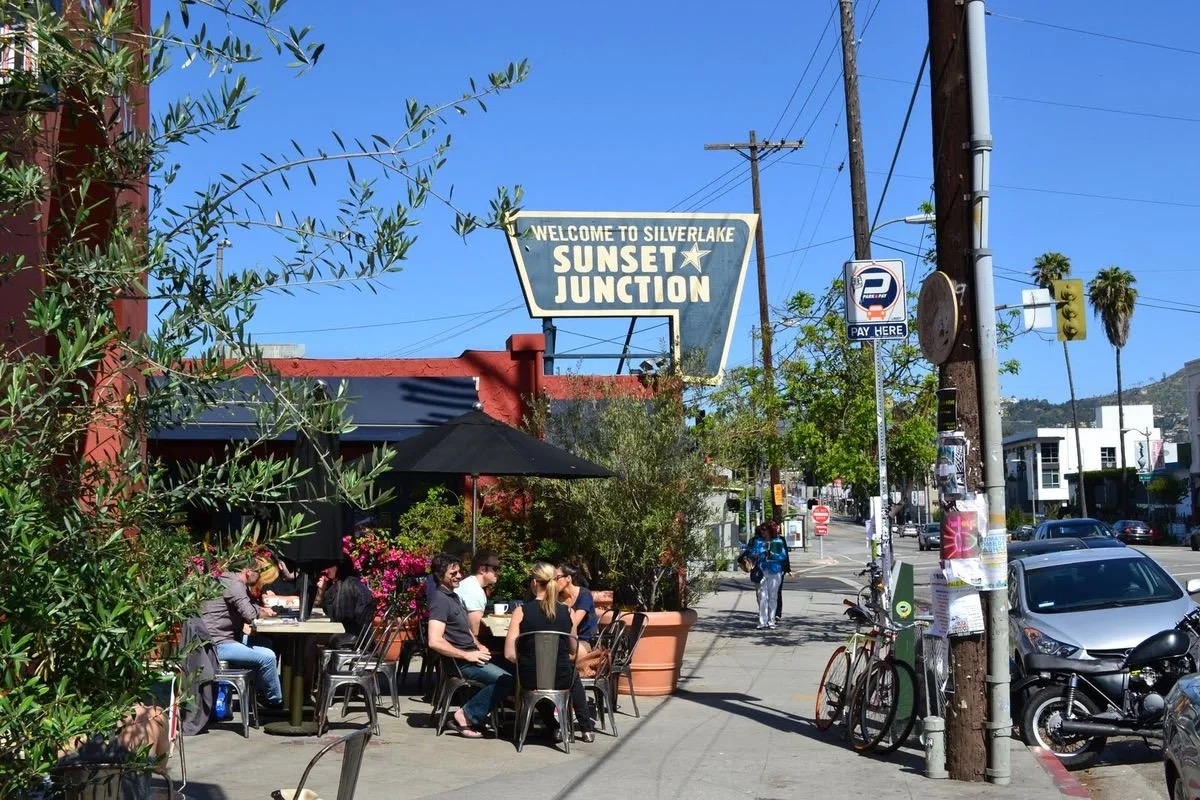 Neighbors gathered at a sidewalk café beneath the Sunset Junction sign