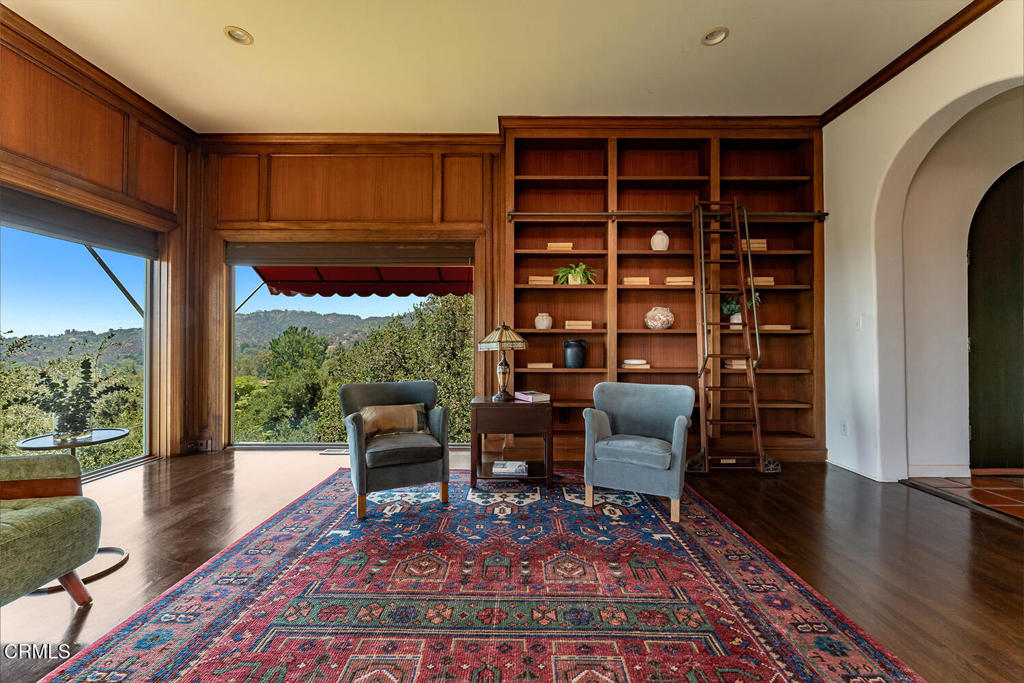 Wood-paneled library with floor-to-ceiling built-in shelves and a rolling ladder