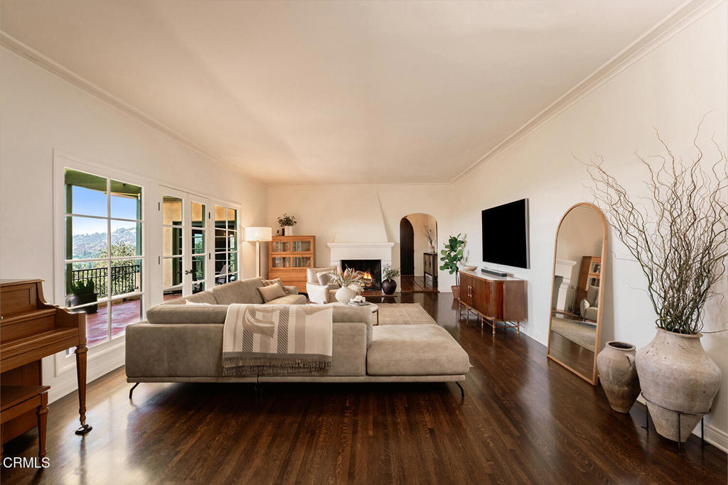 Living room with a fireplace, arched doorway, hardwood floors, and canyon views