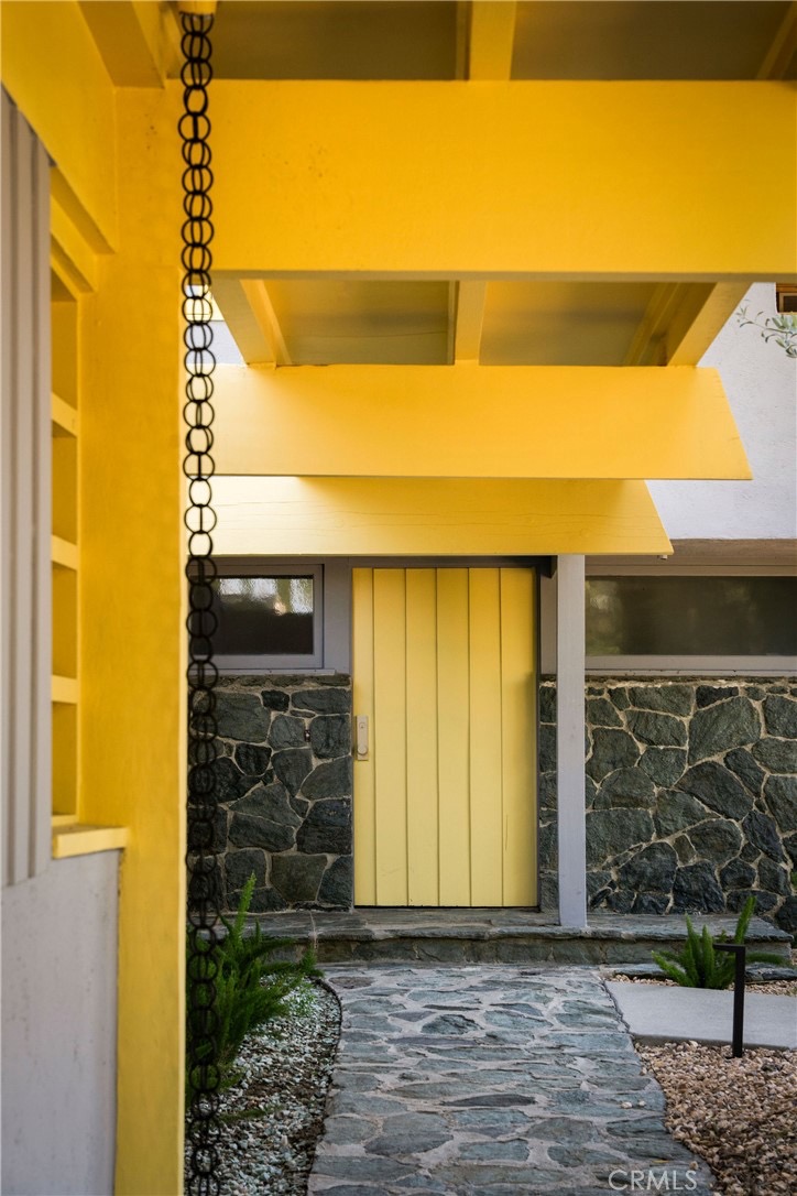 Yellow front door and black iron rain chain at the Van Dekker House