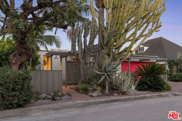 Hot pink garage door behind cactus and yucca at the entrance to 2276 Moreno Drive