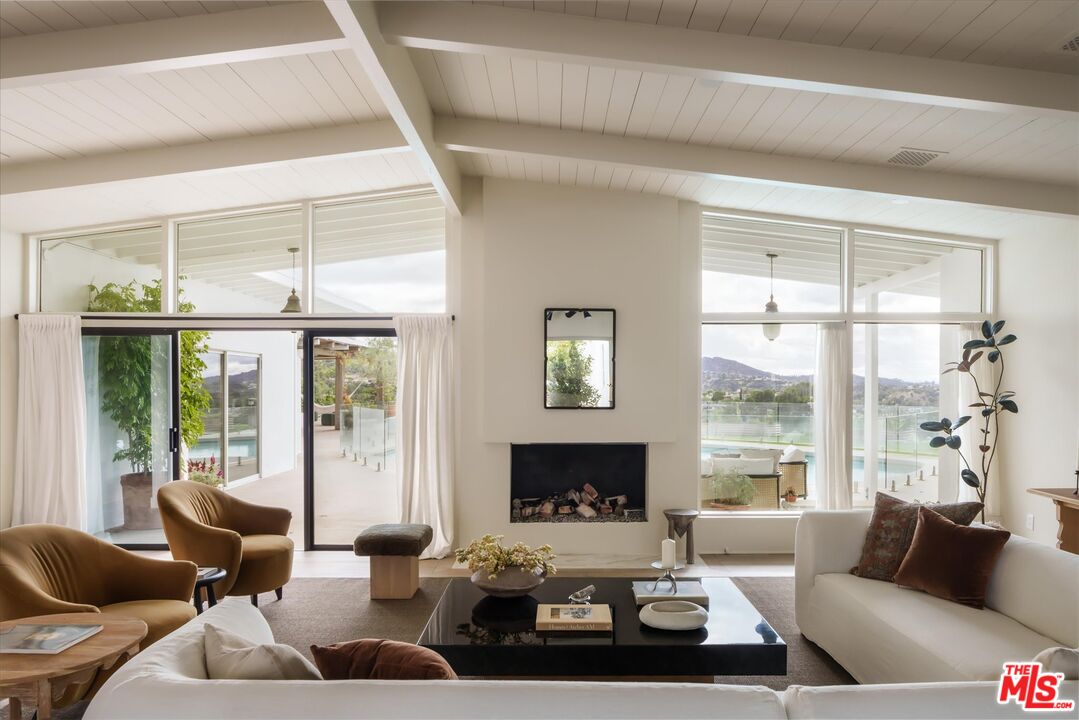 Vaulted post-and-beam living room with walls of glass and canyon views
