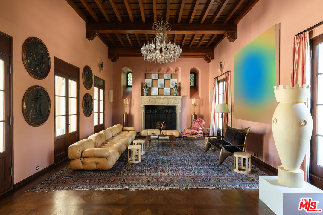 Dusty salmon-pink formal room with original wood-beamed ceiling, chandelier, and bold contemporary art at 402 S Las Palmas Ave