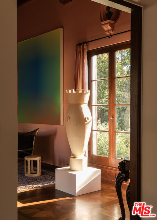Close view of the saturated blue-and-yellow contemporary artwork and sculptural vase in the salmon-pink formal room at 402 S Las Palmas Ave