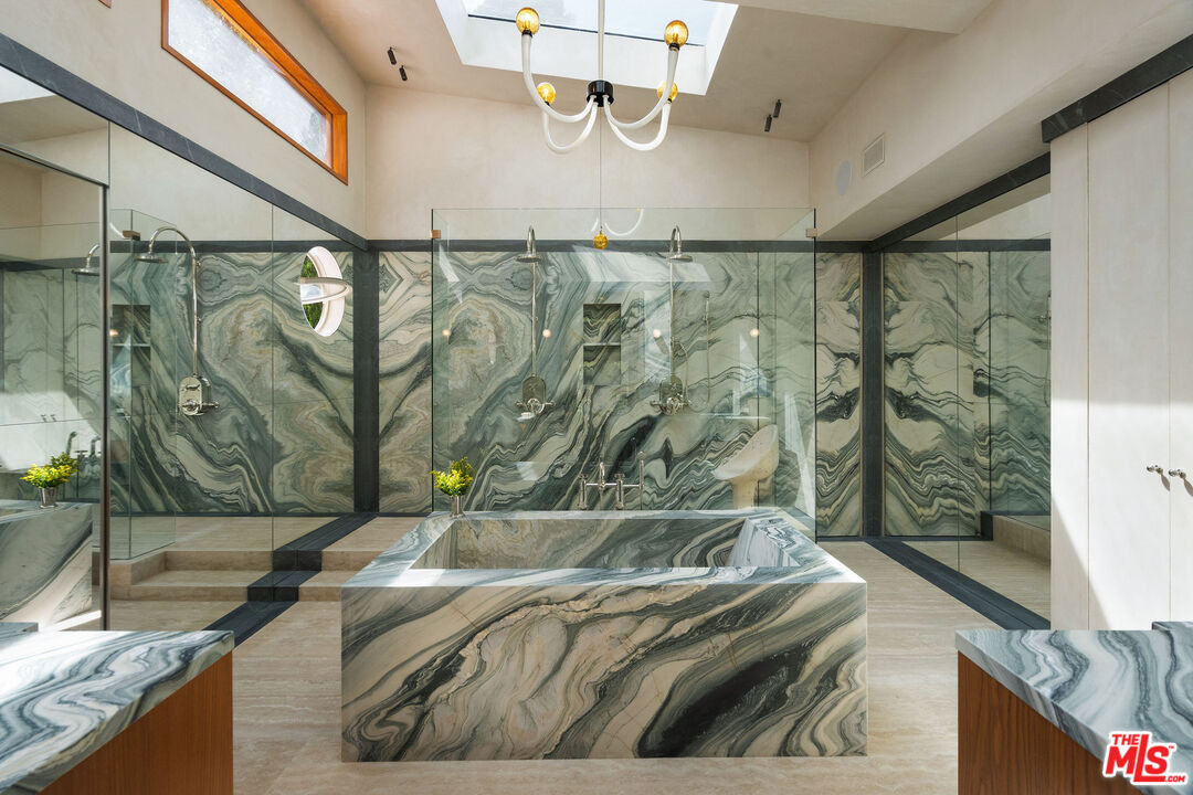 Primary bathroom with book-matched green-and-white marble walls and a sculptural marble tub at 7728 Woodrow Wilson Dr