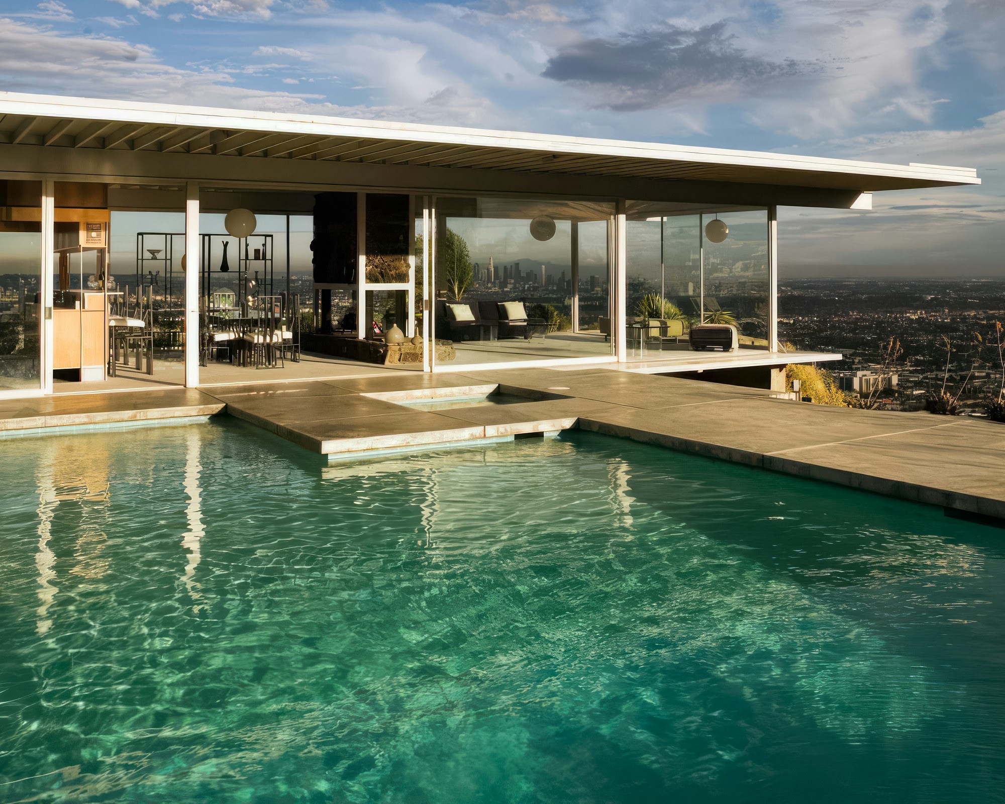 A glass-walled Los Angeles midcentury home with a bright swimming pool overlooking the city